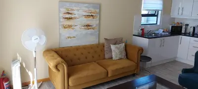 a living room with a couch and a kitchen at Shalom Self catering in Cape Town