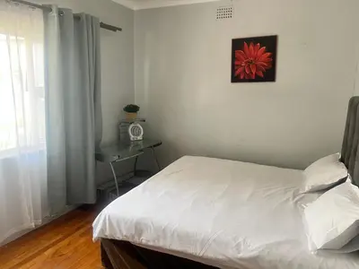 a bedroom with a white bed with a red flower on the wall at izuba Lodge in Cape Town
