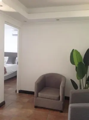 a chair in a living room with a bedroom at Sikelela Guest House in Cape Town