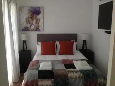 a bedroom with a bed with a painting on the wall at Sikelela Guest House in Cape Town