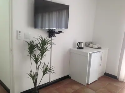 a room with a plant and a television on the wall at Sikelela Guest House in Cape Town