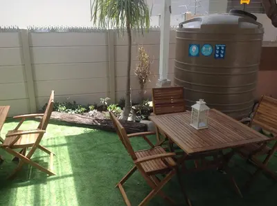 a patio with a table and chairs and a barrel at Sikelela Guest House in Cape Town