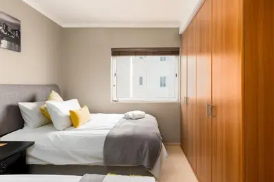 a bedroom with a bed and a wooden cabinet at Horizon Bay 301 by CTHA in Bloubergstrand