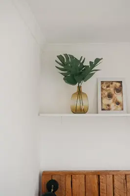 a plant in a gold vase sitting on a shelf at Rooi Els Sea Cottage in Rooiels