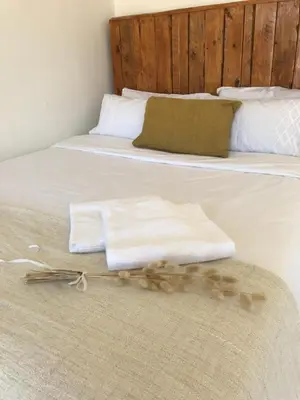 a bed with two towels and a pile of flowers on it at Rooi Els Sea Cottage in Rooiels