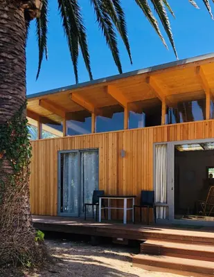 a house on the beach with a table and chairs at Palm and Pine Cottage in Cape Town