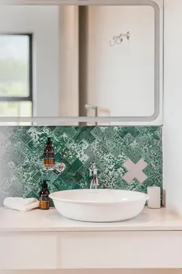 a white sink in a bathroom with a green tiled wall at Ludus Magnus Boutique Hotel in Franschhoek
