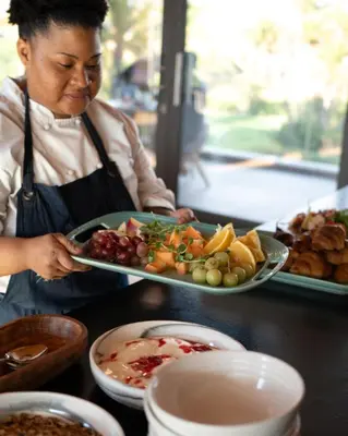 a woman holding a plate of food on a counter at Ludus Magnus Boutique Hotel in Franschhoek