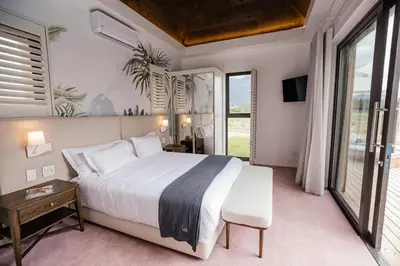 a bedroom with a large bed and a large window at Ludus Magnus Boutique Hotel in Franschhoek