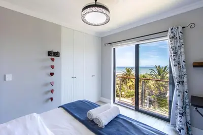 a bedroom with a bed and a large window at Apartment18Lifestyle Gordons Bay Beachfront in Gordonʼs Bay