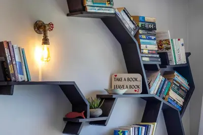 a book shelf filled with books next to a wall at Apartment18Lifestyle Gordons Bay Beachfront in Gordonʼs Bay