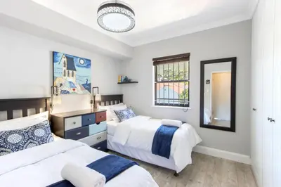 a bedroom with two beds and a mirror at Apartment18Lifestyle Gordons Bay Beachfront in Gordonʼs Bay
