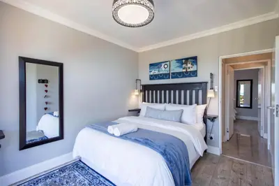a bedroom with a large bed and a mirror at Apartment18Lifestyle Gordons Bay Beachfront in Gordonʼs Bay