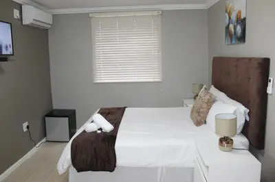 a bedroom with a bed and a table and a window at 103onWallace Self Catering Guest House in Cape Town