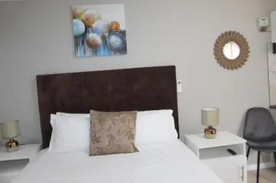 a bedroom with a white bed with a wooden headboard at 103onWallace Self Catering Guest House in Cape Town