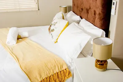 a white bed with white pillows and a yellow blanket at 103onWallace Self Catering Guest House in Cape Town