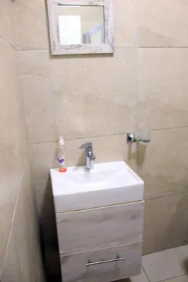 a bathroom with a sink and a mirror at 103onWallace Self Catering Guest House in Cape Town