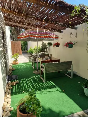 a patio with a bench and an umbrella and plants at Barlinka lane Selfcatering flatlet , Somerset West in Cape Town