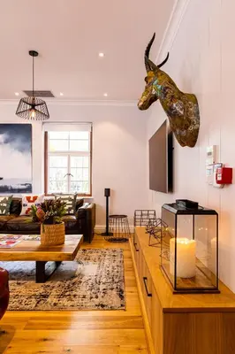a living room with a table and a horse head on the wall at Luxury Apartments - Rozenhof Villa in Stellenbosch