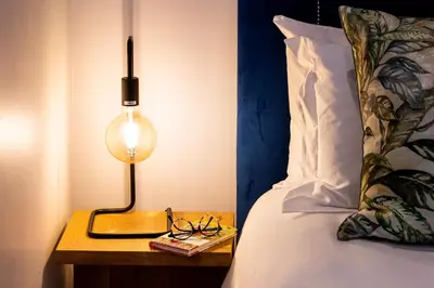 a lamp on a night stand next to a bed at Luxury Apartments - Rozenhof Villa in Stellenbosch