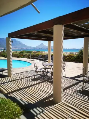 a patio with a table and chairs next to a pool at Cape Town Family Beachfront Apartment Leisure Bay in Cape Town