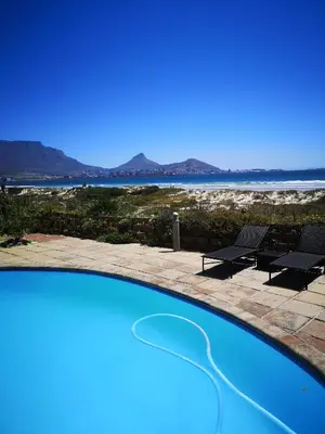 a swimming pool with a view of the ocean at Cape Town Family Beachfront Apartment Leisure Bay in Cape Town