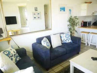 a living room with a blue couch and a mirror at Cape Town Family Beachfront Apartment Leisure Bay in Cape Town