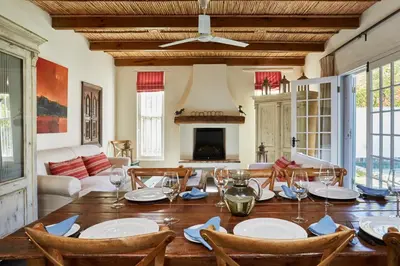 a dining room with a table with chairs and a fireplace at Tockie's Cottage in Franschhoek