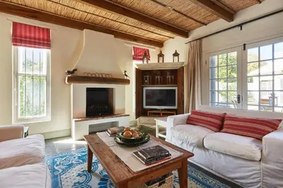 a living room with a white couch and a fireplace at Tockie's Cottage in Franschhoek