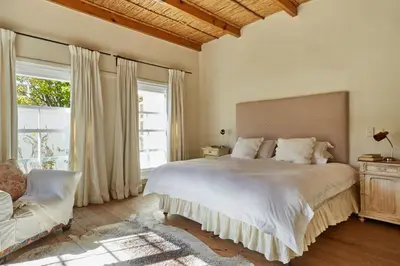 a bedroom with a large bed with a large window at Tockie's Cottage in Franschhoek