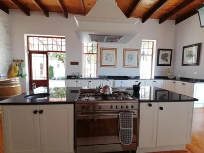 a kitchen with white cabinets and a stove top oven at Avontuur Manor House and Wine Estate in Somerset West