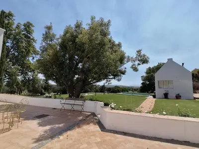 a white fence with a tree and a house at Avontuur Manor House and Wine Estate in Somerset West