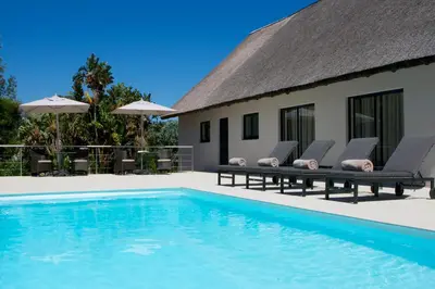 a villa with a swimming pool and lounge chairs at Cape Vermeer in Somerset West