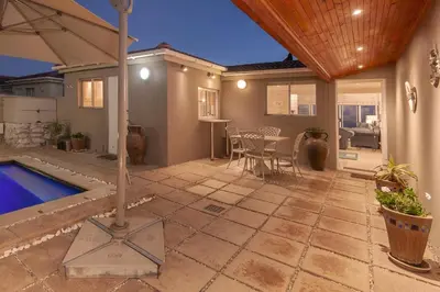 a patio with a swimming pool and a house at Hermanus Haven, entire home, on the sea, private pool, secure in Hermanus