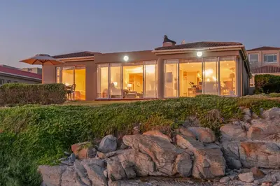 a house on a hill with rocks in front of it at Hermanus Haven, entire home, on the sea, private pool, secure in Hermanus