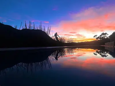 a person riding a bike next to a body of water at The Guardian Hermanus Luxury Self-Catering Hemel en Aarde Valley in Hermanus