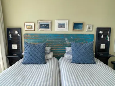 two beds with blue and white pillows in a bedroom at By Die See in Gordonʼs Bay