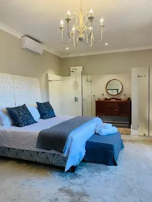 a large bedroom with a large bed and a chandelier at Bonne Chance Cottage in Paarl