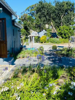 a garden with a table and chairs and flowers at Bonne Chance Cottage in Paarl