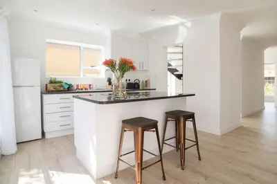 a kitchen with a counter and two stools at Sunset Beach Living Guesthouse in Cape Town