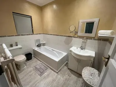 a bathroom with a tub and a toilet and a sink at Sea front Rocky Pools in Bettyʼs Bay