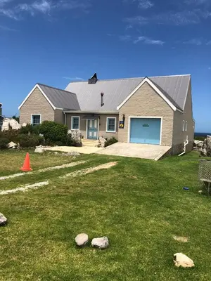 a house with a yard with rocks in front of it at Sea front Rocky Pools in Bettyʼs Bay