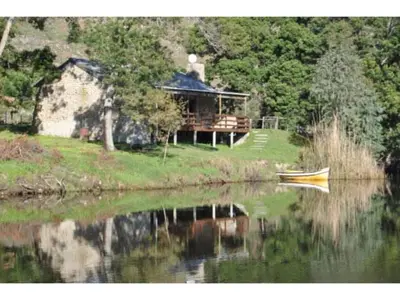 a house on the shore of a lake with a boat at River Edge in Romansrivier