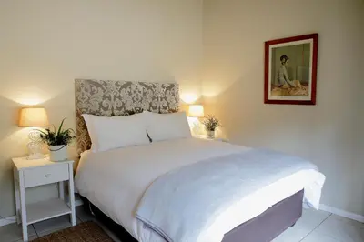 a bedroom with a white bed and a picture on the wall at River Edge in Romansrivier