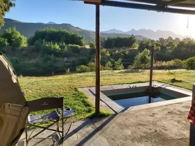 a chair and a swimming pool with a view of the mountains at River Edge in Romansrivier