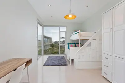 a white bedroom with a bunk bed and a desk at Blueview on Silversand in Clareport