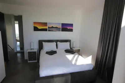 a bedroom with a white bed with two pictures on the wall at Dolphin Beach Villa E24 direct access to the beach in Cape Town