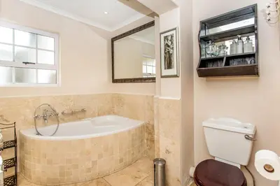 a bathroom with a tub and a toilet and a mirror at Invergara in Cape Town