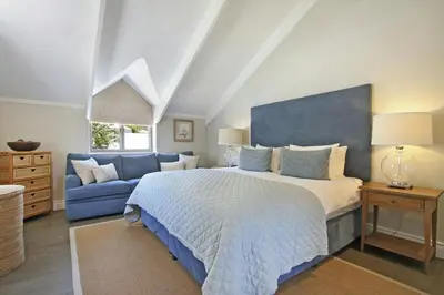 a bedroom with a bed and a blue couch at Le Bas De Laine in Franschhoek