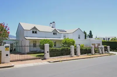 a white house with a wrought iron fence at Le Bas De Laine in Franschhoek